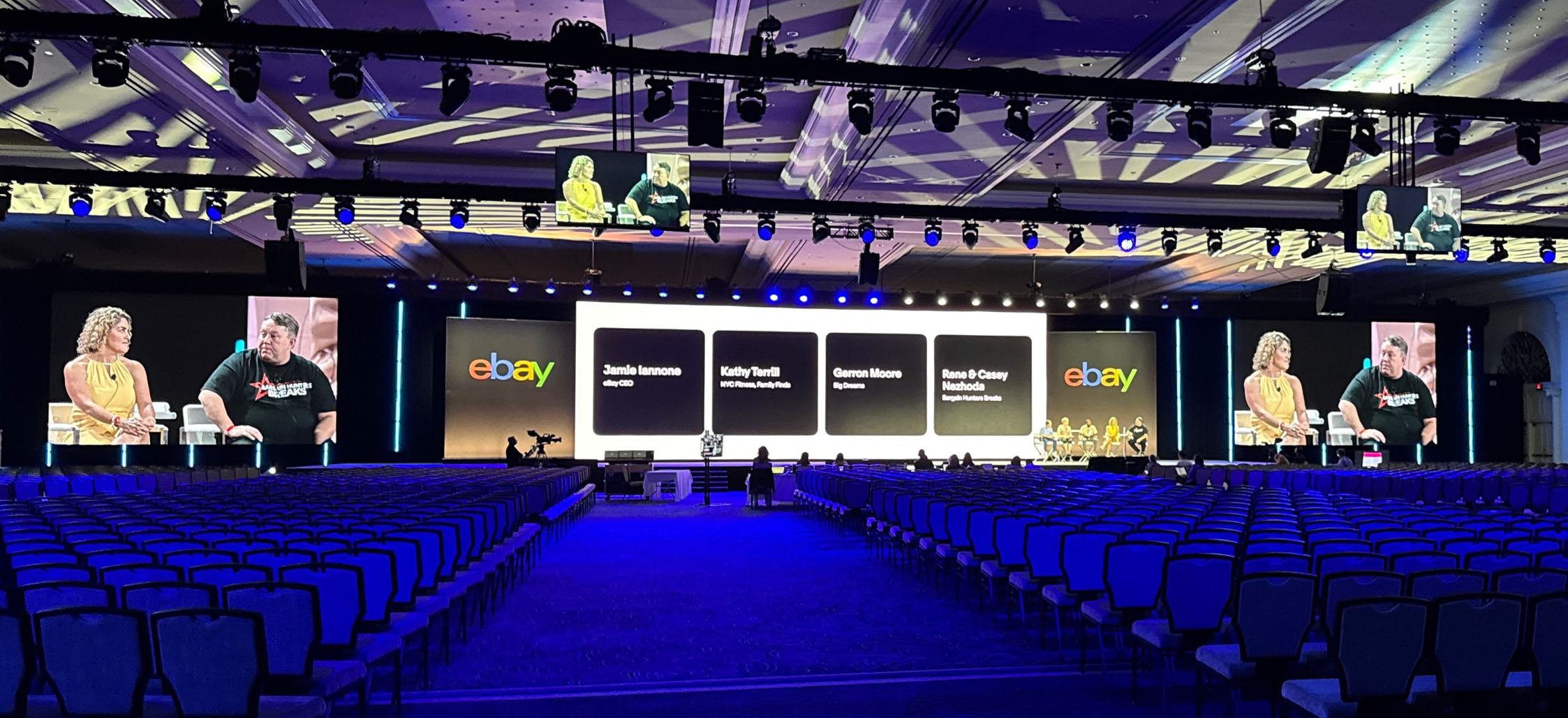 A wide image of the Keynote Ballroom for the 2025 eBay Open in Las Vegas. Multiple rows of lights hang over 4000 chairs and three large LED walls overlook the stage.